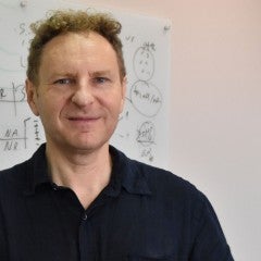 Valentin Dragoi standing in front of whiteboard