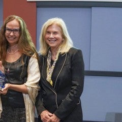 Three people standing in a row holding an award
